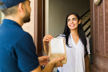 Happy Latin young woman receiving a delivery of medication from a courier at her doorstep