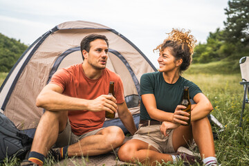 Happy couple camp and drink beer have a fun together time