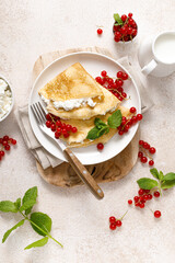 Crepes or thin pancakes with cheese cottage or curd and fresh red currant berries, top view