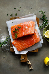 Salmon. Fresh raw salmon fish fillet with cooking ingredients, herbs and lemon on dark background,...