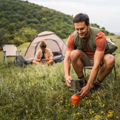 Boyfriend prepare coffee while camp with girlfriend in the background