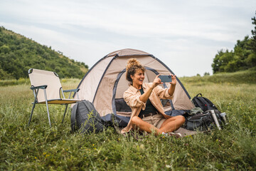 Adult young woman take a picture on mobile phone while camping