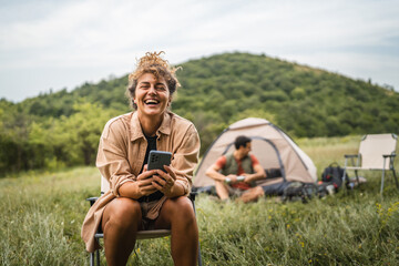 Girlfriend use mobile phone on camp with boyfriend in the background