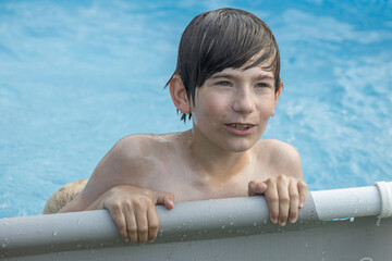 A boy with wet hair is enthusiastically swimming in a pool, giving a thumbs-up gesture. Another...