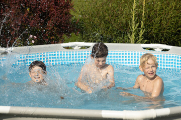 A boy with wet hair is enthusiastically swimming in a pool, giving a thumbs-up gesture. Another...