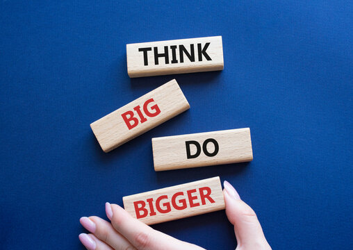 Think Big Do Bigger symbol. Wooden blocks with words Think Big Do Bigger. Businessman hand. Beautiful deep blue background. Business and Think Big Do Bigger. Copy space.