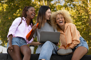 Multiethnic happy students enjoying time after school class in the university campus while doing some homework