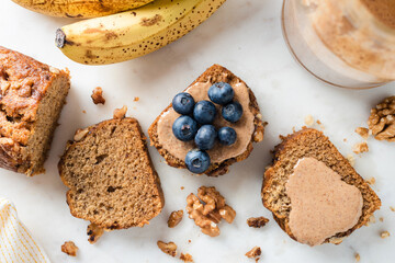 Banana bread slices topped with almond butter and blueberries. Vegan paleo banana bread cake, top view