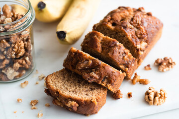 Vegan paleo banana bread with walnuts on white marble background, closeup view