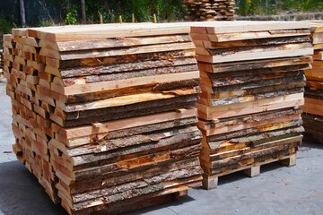 A stack of boards. Wooden planks close up in a lumber yard. Board background.Wooden boards and beams. Wood for building a house. Construction material. Wood warehouse.