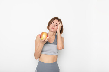 Close up portrait of pretty woman in sportswear holding apple isolated on white background. Healthy lifestyle concept