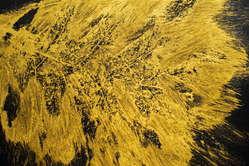 Messy brush strokes made of gold acrylic paint on black paper background