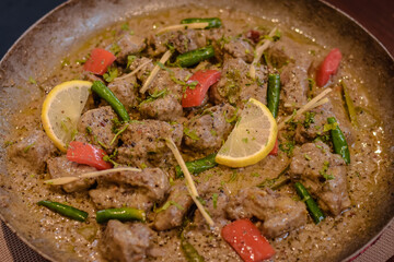 Mutton karahi topped with lemon slices green chilli ginger and tomtao 