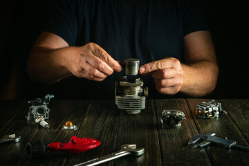 Man repairing a trimmer engine. Replacing an engine piston on a table at home.