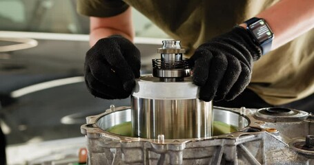 Close-up of a mechanic's hands working on the internal parts of an electric car motor. Mechanical maintenance in an auto service garage. EV repair and service concept.