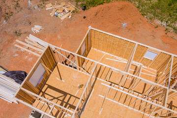 Construction work in progress on an unfinished house with wooden framing beams