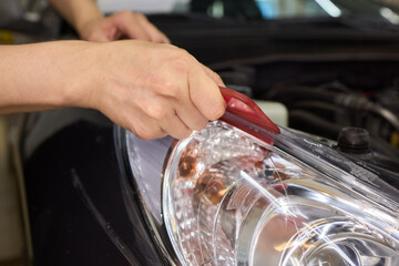 Protective film applied to car bumper in detailing workshop for safety and maintenance
