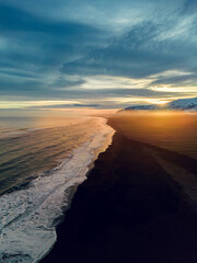 Aerial view of nordic black sand beach in iceland, beautiful ocean shoreline and beachfront at sunset, creating magical icelandic scenery. Majestic atlantic coast with huge waves smaking.