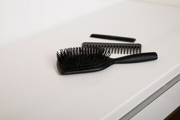 Used hair brush and combs with some hair on white table, head skin hygiene