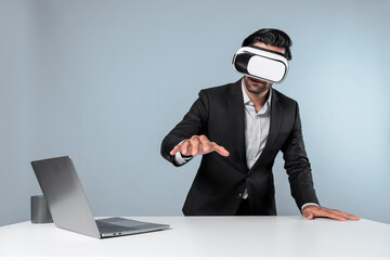 Professional project manager looking by using VR goggle while sitting at laptop. Skilled business...