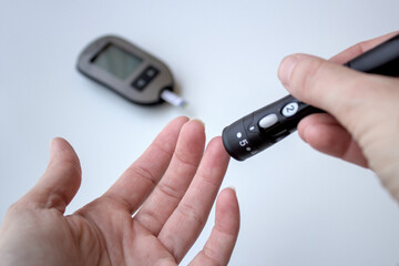 Diabetes screening test. Patient measuring blood glucose by pricking his finger at home. Blood...