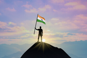 Waving flag of India at the top of a mountain summit against sunset or sunrise. India flag for Independence Day.