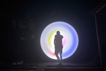 One person standing alone against a Colourful circle light painting as the backdrop	