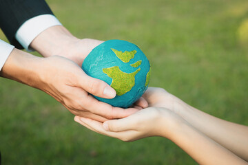 Businessman hand giving Earth globe to little boy as Earth day concept as corporate social...