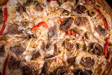 Close-up of a hand taking a slice of vegetarian pizza with onions, bell pepper, and vegetables on a wooden board.