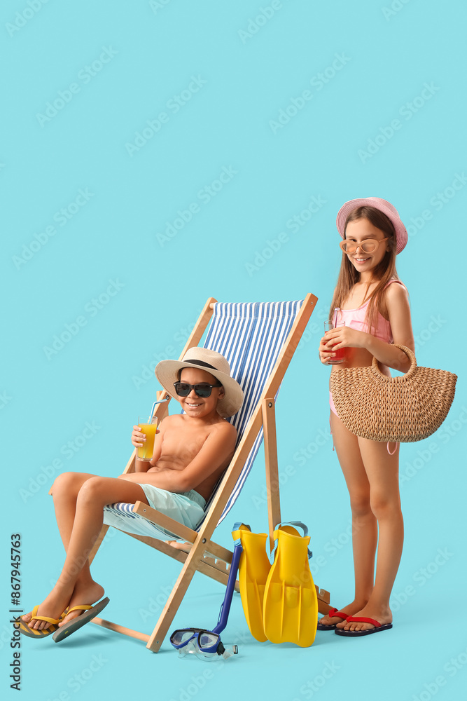 Poster cute little children in swimsuit, sunglasses with glasses of juice, flippers and sun lounger on blue