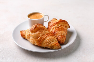 Plate with tasty croissants and cup of coffee on white background
