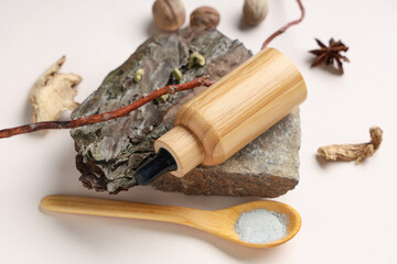 Bottle of natural cosmetic product, stone and spoon with clay on white background