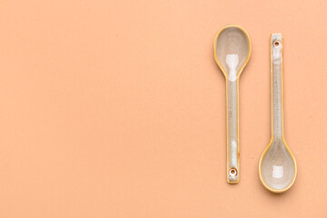 Ceramic spoons on color background