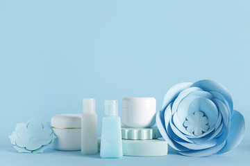Facial cosmetic products composition with paper flowers on blue background
