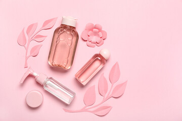 Composition of cosmetic products with paper flowers and leaves on pink background