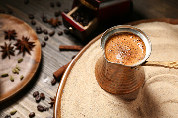 Turkish coffee cooking in sand on wooden background