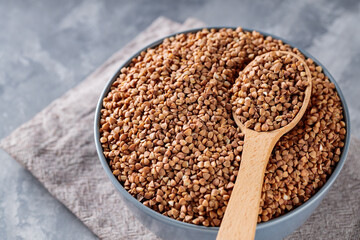 Buckwheat Grains in Wooden Spoon on Gray Background, Close Up