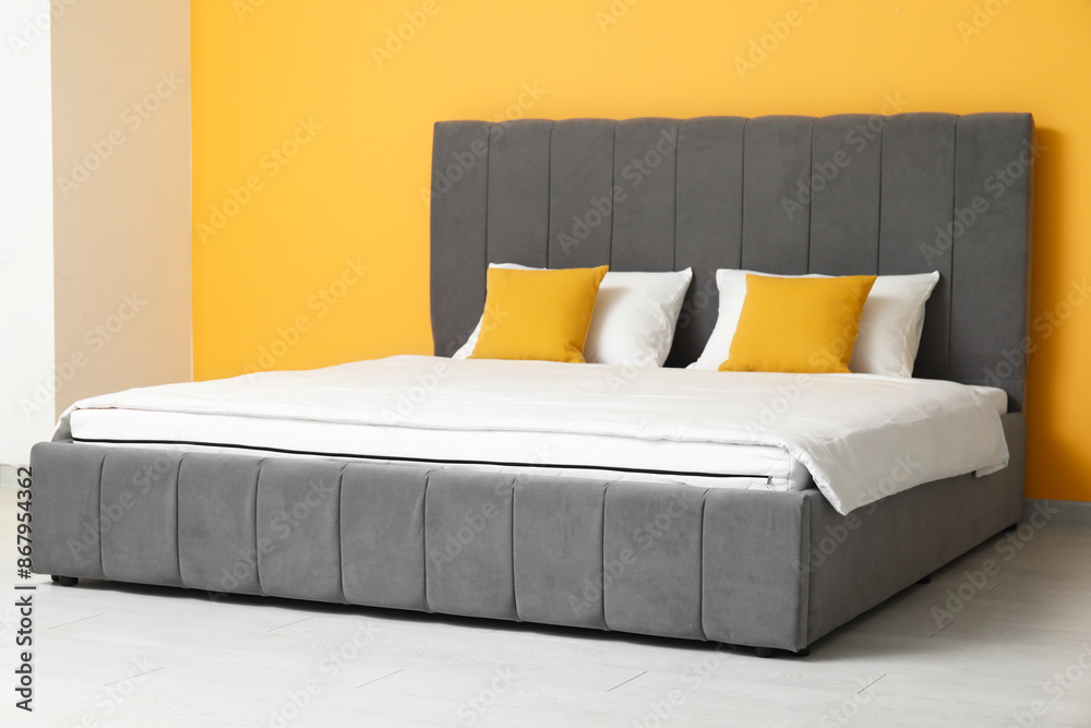 Sticker New orthopedic mattress with blanket on stylish bed near yellow wall in room