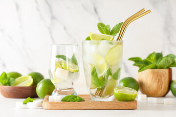 Glasses of fresh Mojito cocktail with limes and mint on white background