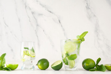Glasses of fresh Mojito cocktail with limes and mint on white background