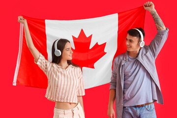 Young couple in headphones with flag of Canada on red background