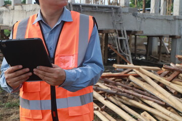 A team of engineers inspects beam work and installs concrete pillars according to the blueprint.