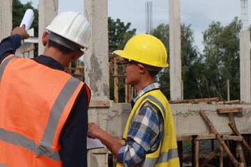 A team of engineers inspects beam work and installs concrete pillars according to the blueprint.