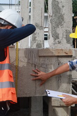 A team of engineers inspects beam work and installs concrete pillars according to the blueprint.