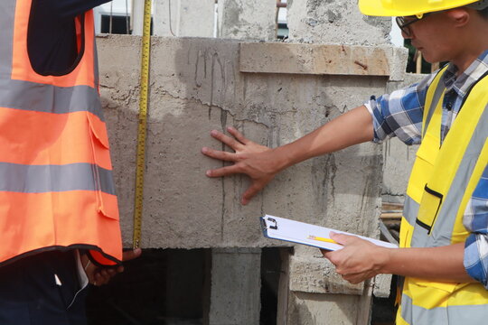 A team of engineers inspects beam work and installs concrete pillars according to the blueprint.