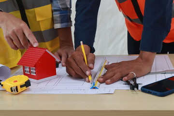 A team of engineers inspects beam work and installs concrete pillars according to the blueprint.