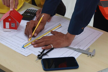 A team of engineers inspects beam work and installs concrete pillars according to the blueprint.