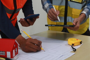 A team of engineers inspects beam work and installs concrete pillars according to the blueprint.