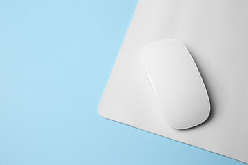 One wireless mouse with mousepad on light blue background, top view. Space for text