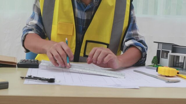 A male engineer inspects a structural model of a house at his workstation, ensuring compliance with design specifications and safety standards.